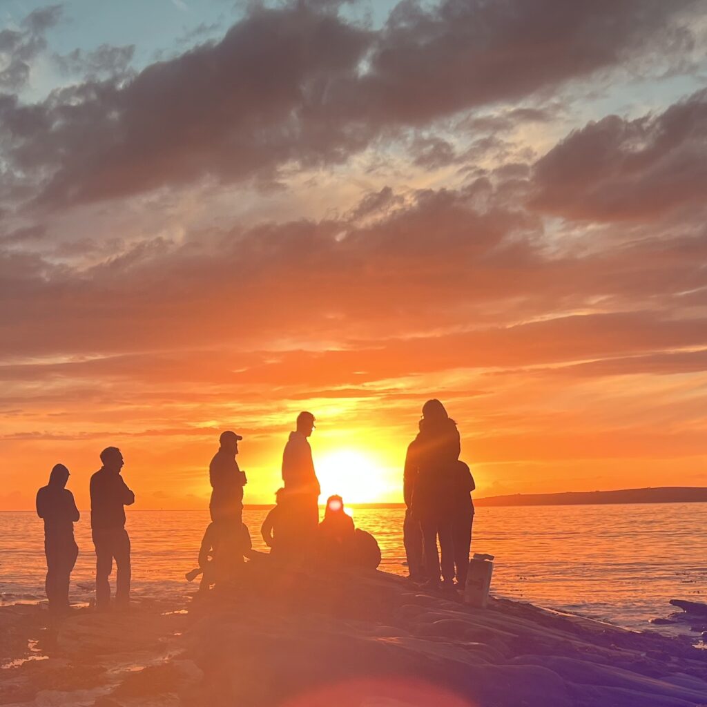 A group of people in front of the sunset