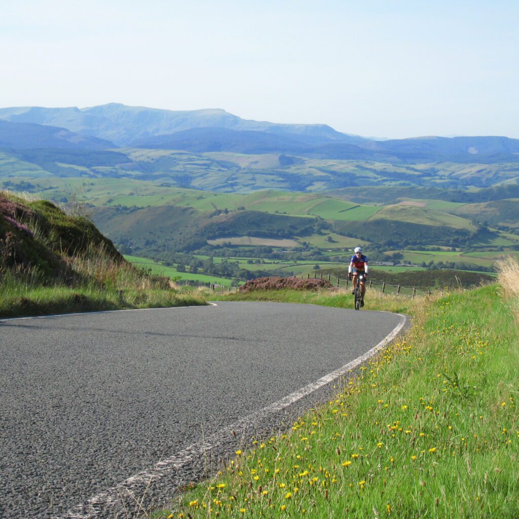 Rider coming up the hill with a beautiful view behind them 