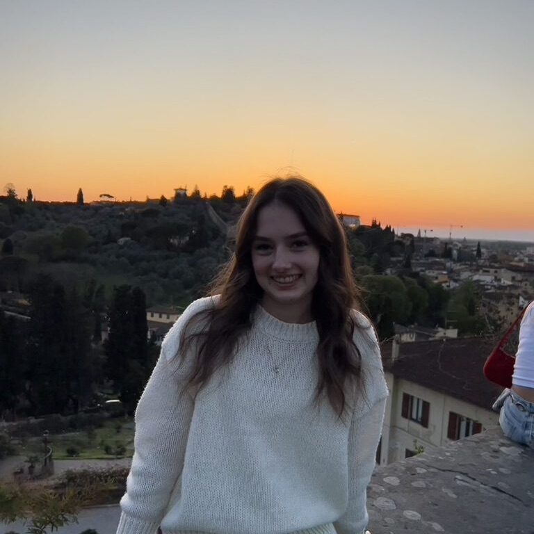 A woman smiling at the camera in front of a sunset